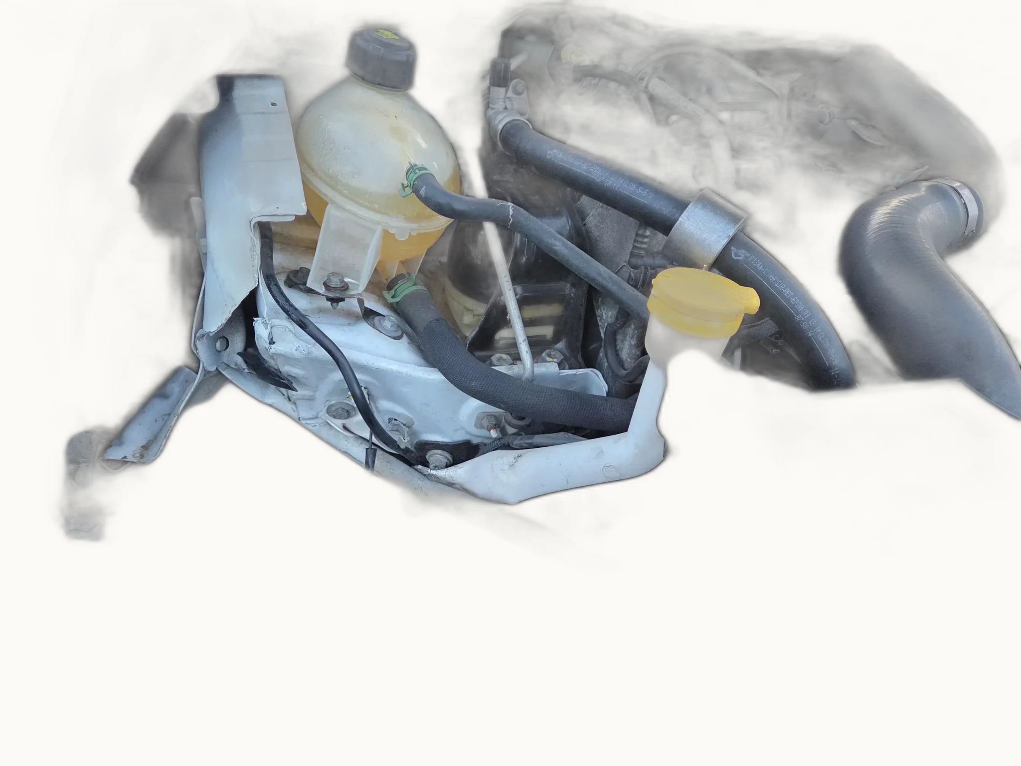 Close-up of a vehicle's engine bay with bumper and front panel removed, exposing the inner structural members, coolant reservoir, and chassis rail
