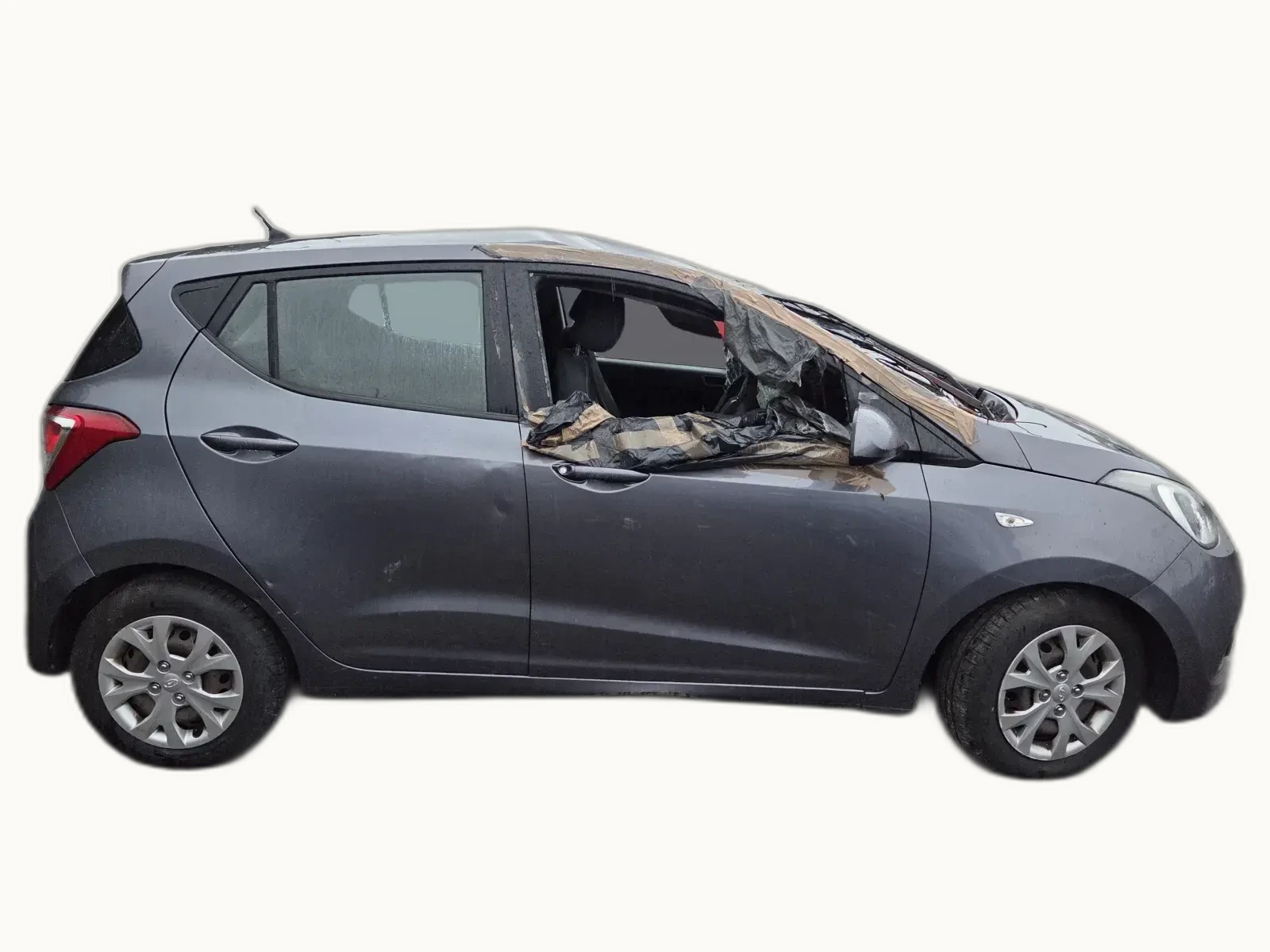 Grey Hyundai i10 photographed in profile against a neutral backdrop, with the smashed windscreen temporarily taped over