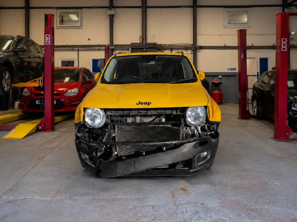 Yellow Jeep Renegade with front-end damage in a UK salvage workshop