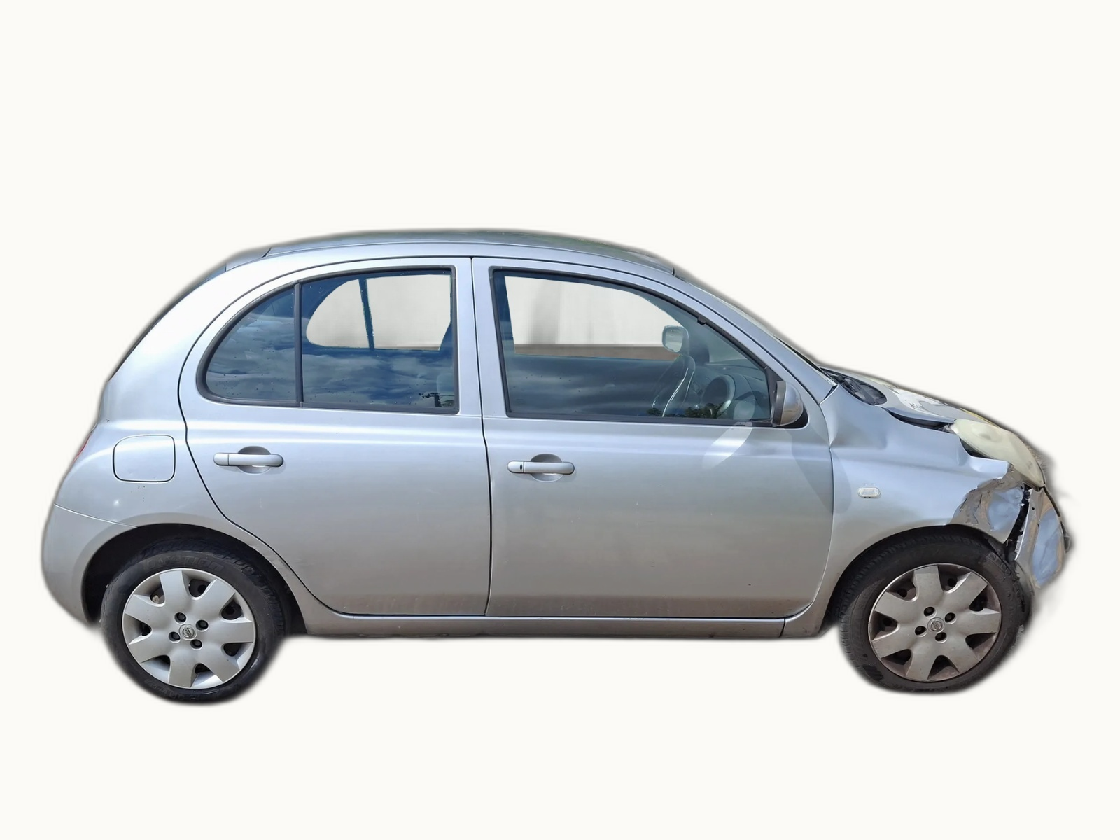 Silver Nissan Micra in profile with light front-corner impact damage, photographed against a neutral studio backdrop