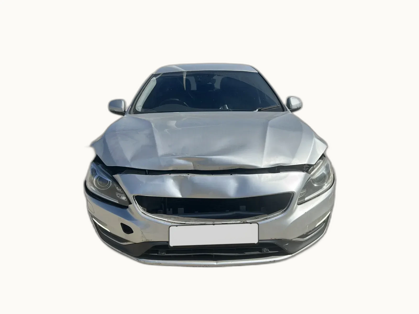 Silver Volvo S60 photographed head-on with the bonnet crumpled, grille collapsed and offside corner deformed, sitting between obvious cosmetic damage and clear structural failure
