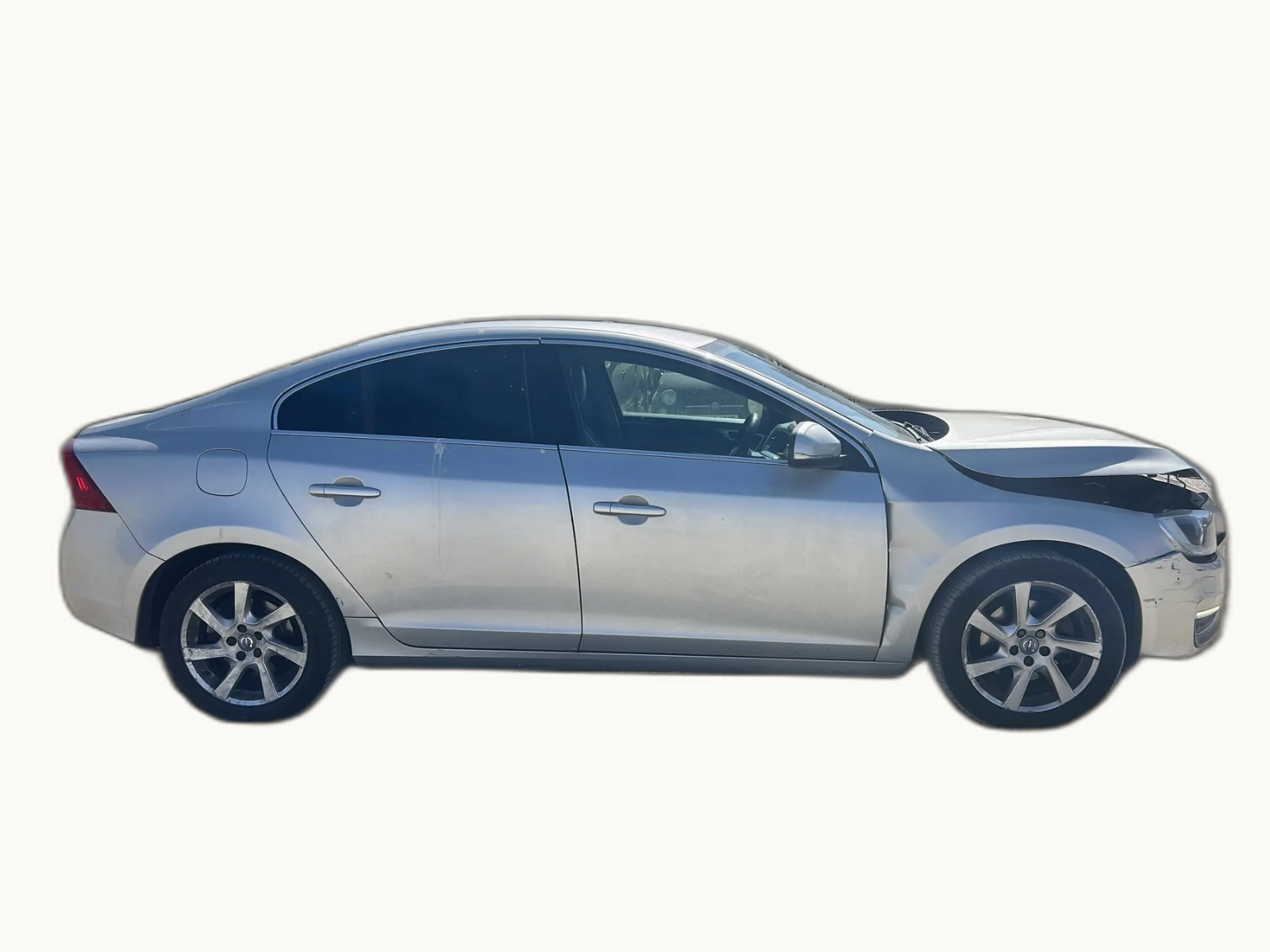 Silver Volvo S60 saloon photographed in profile with visible front-end damage, against a neutral studio backdrop
